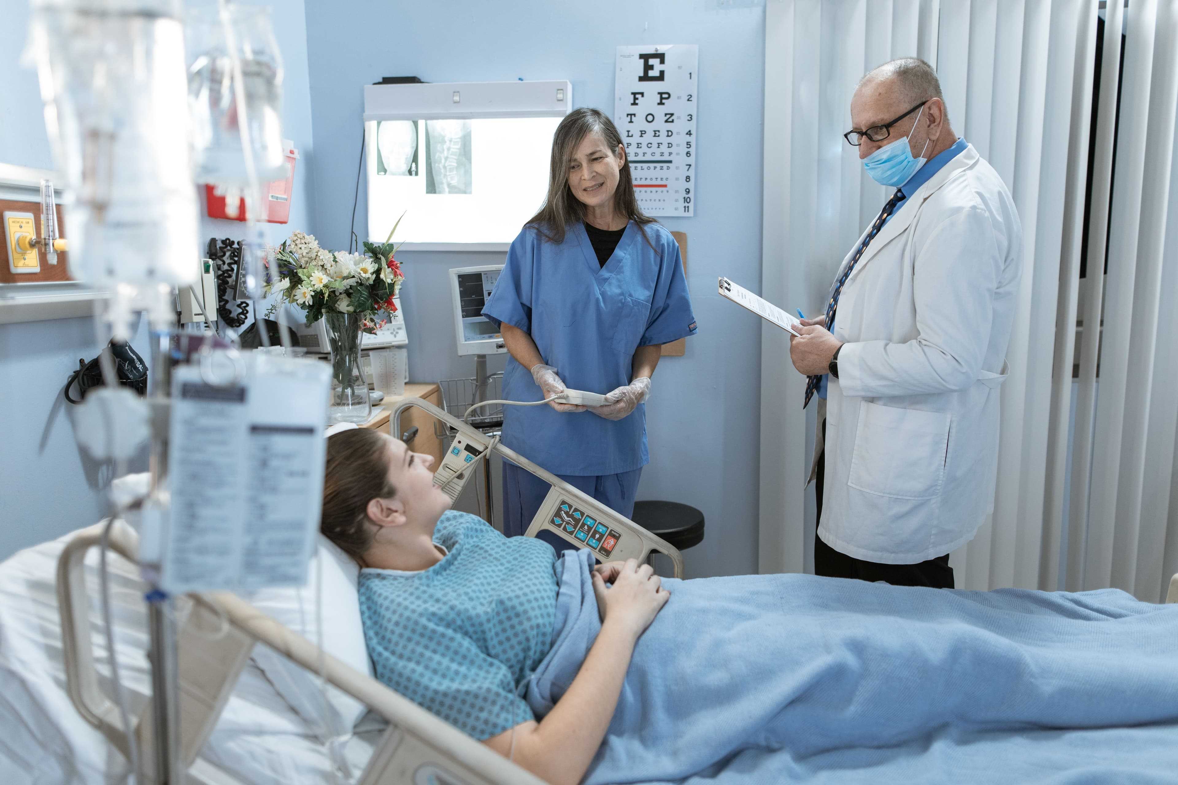 A nurse and doctor speaking with a patient in a hospital room